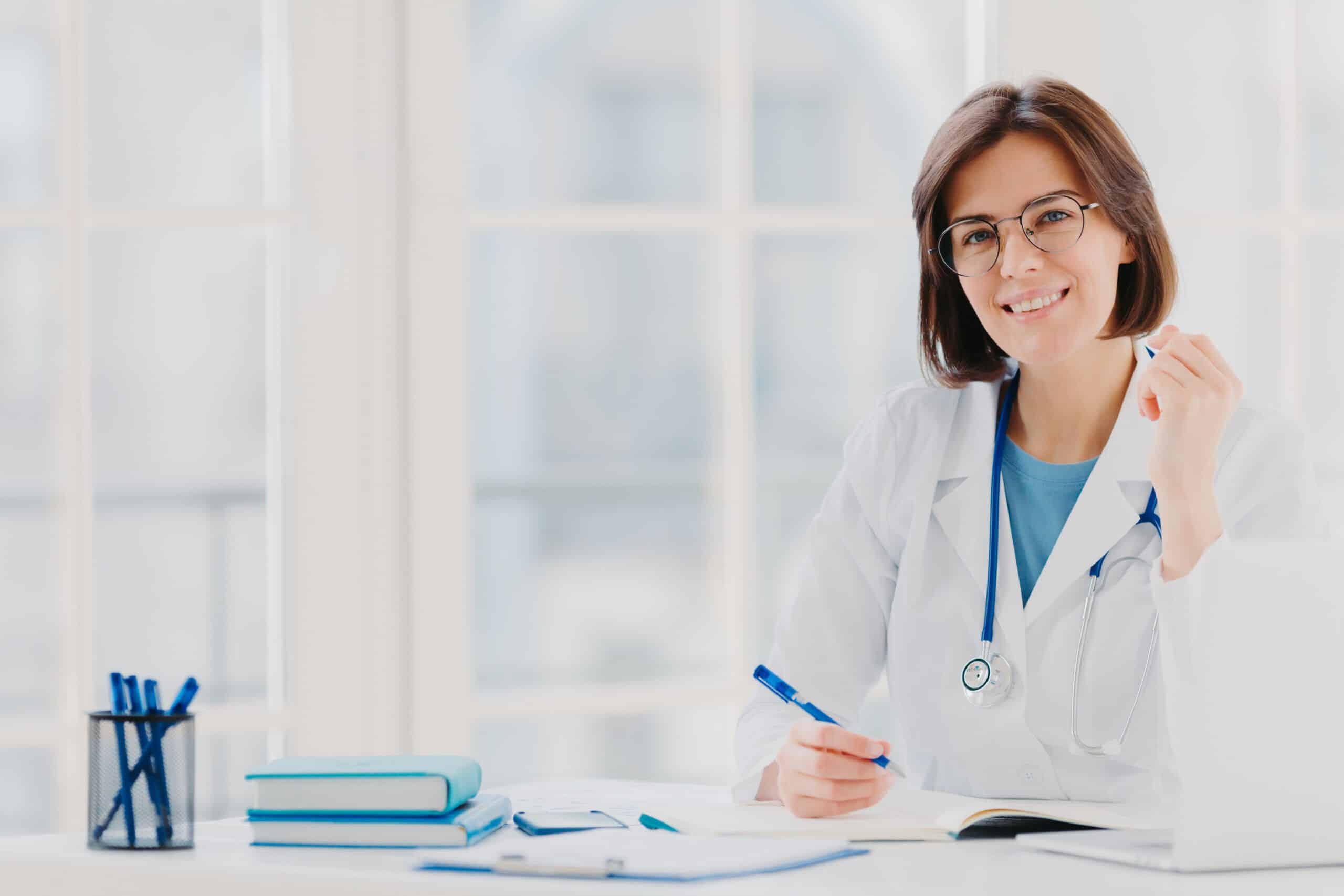 Médica escribiendo un certificado médico en consulta